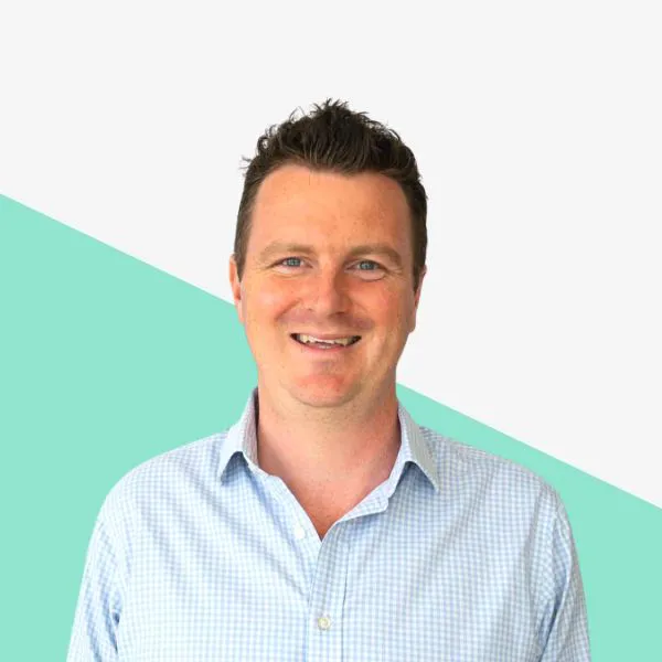 Smiling man in a checked shirt against a light background.
