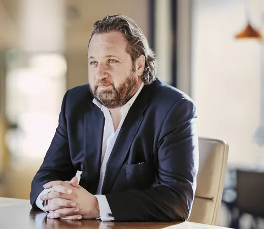 Man with beard in a suit sitting at a table.