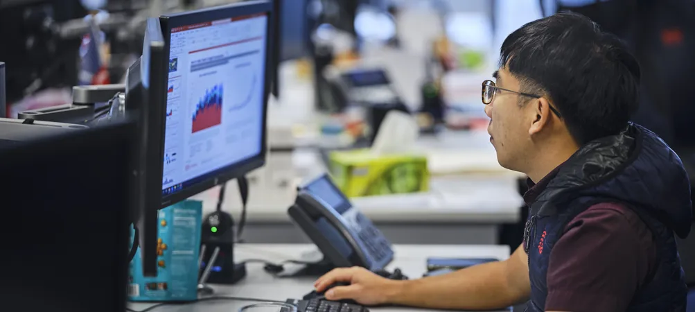 Person working at a desk with computer screens.