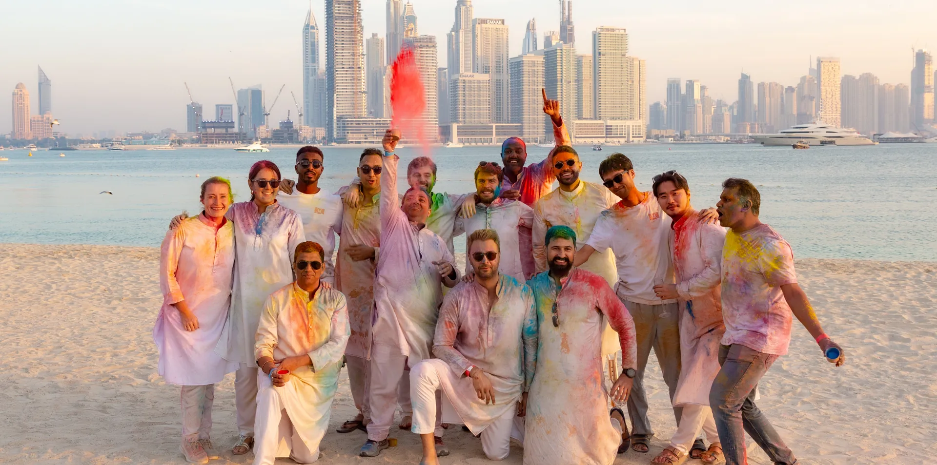 Group celebration on the beach with colored powders.
