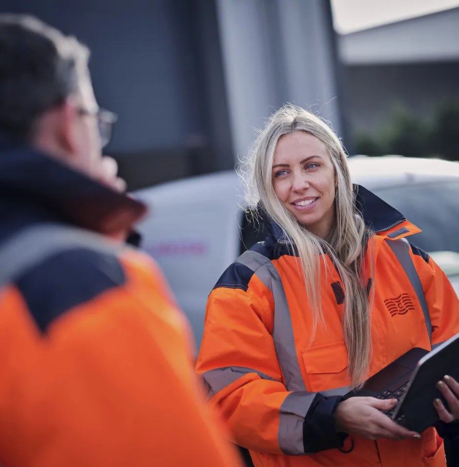 Clarksons female employee in high vis jacket talking to colleagues