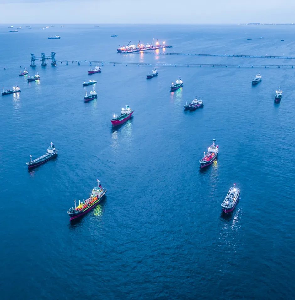 Aerial view of numerous ships in blue water.
