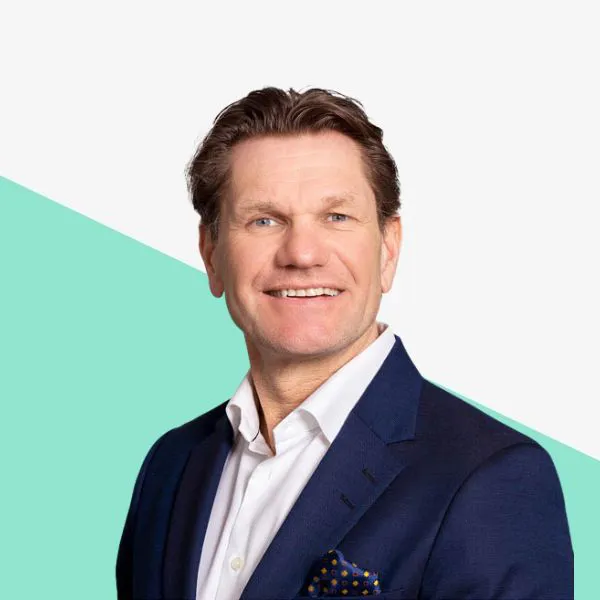 Smiling man in a suit with a light background.