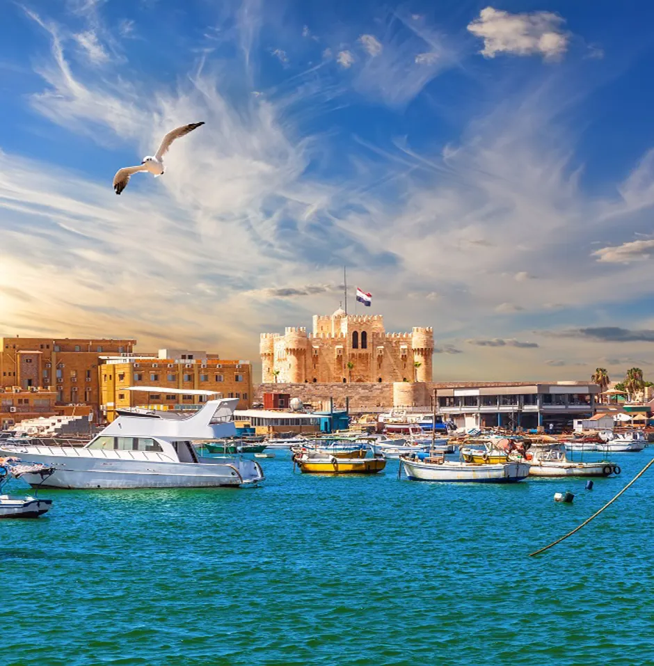 Vibrant harbor with boats and castle at sunset.