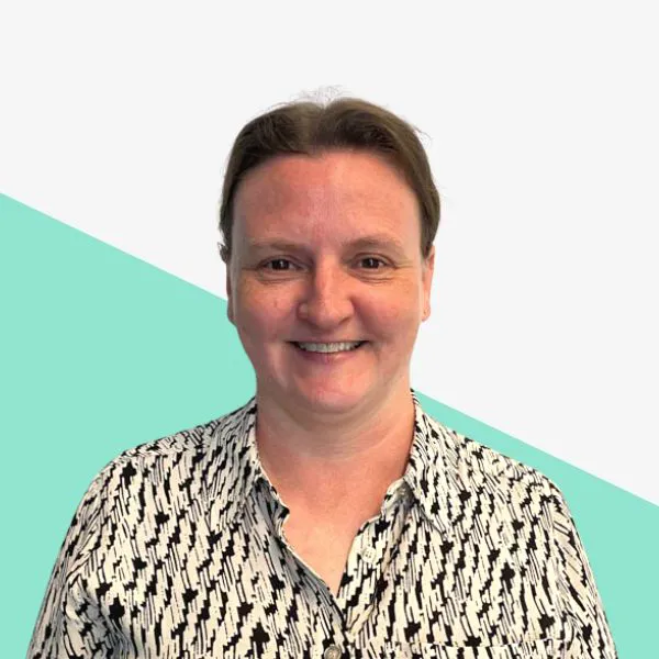 Smiling woman in patterned shirt on a light background.