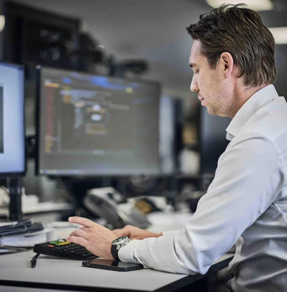 Man working at a desk with computers and documents.