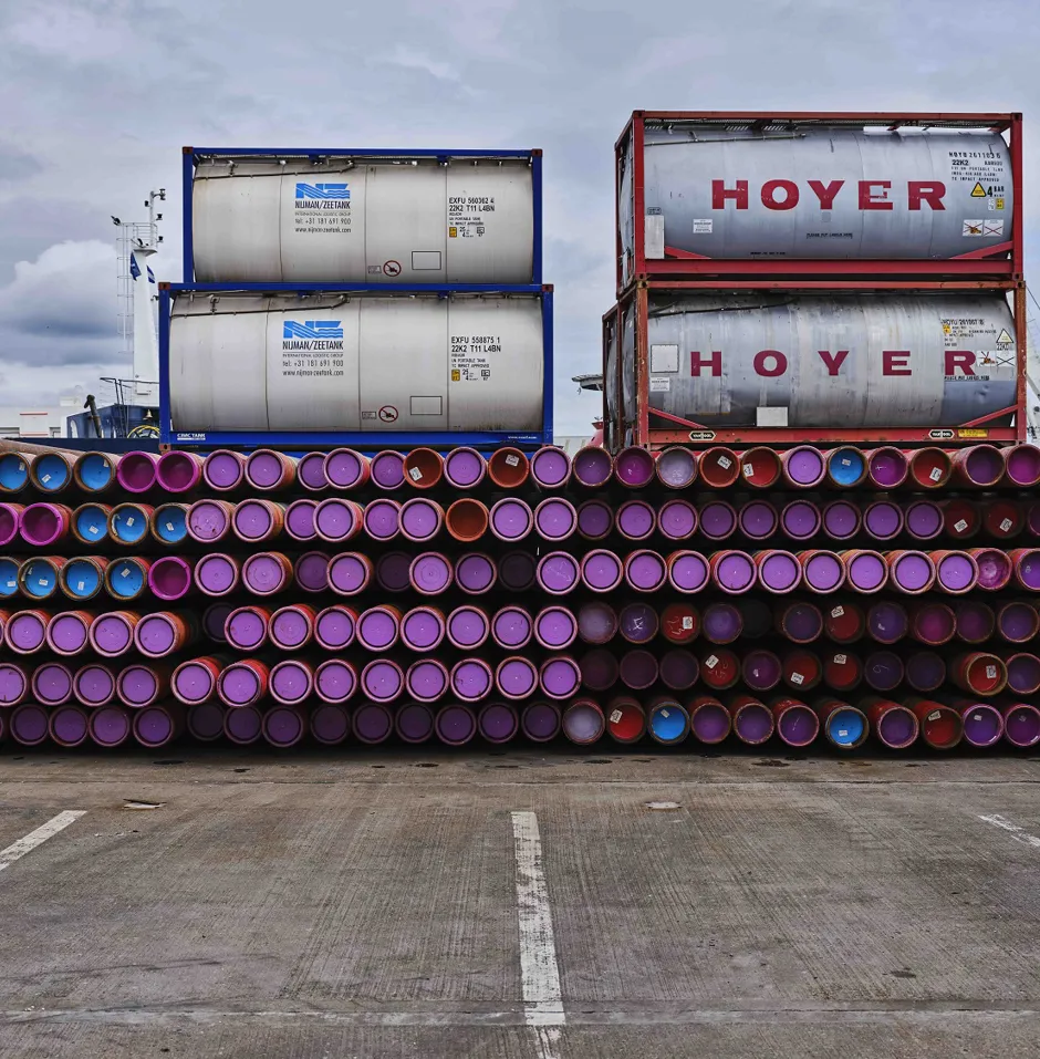 Stacked containers and barrels in a storage area.
